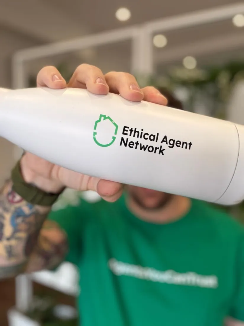 An Ethical Agent Network branded water bottle held up to the camera