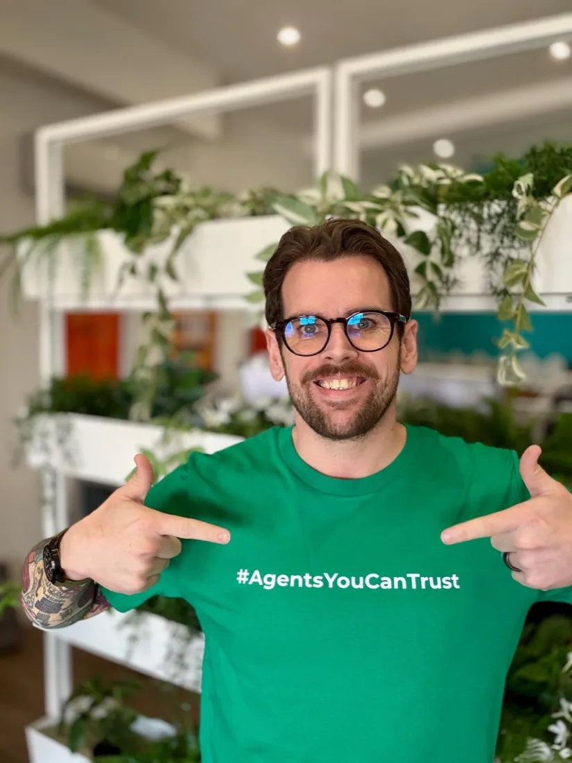 A member pointing at the Agents You Can Trust wording on the front of the shirt