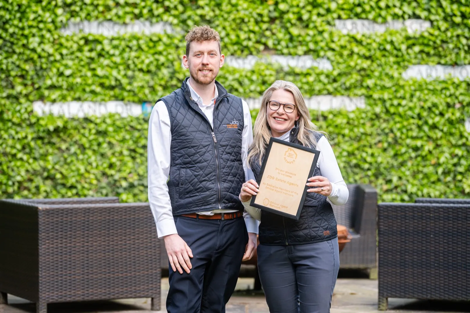 Two directors of a member agency standing outside holding their Ethical Agent Network plaque