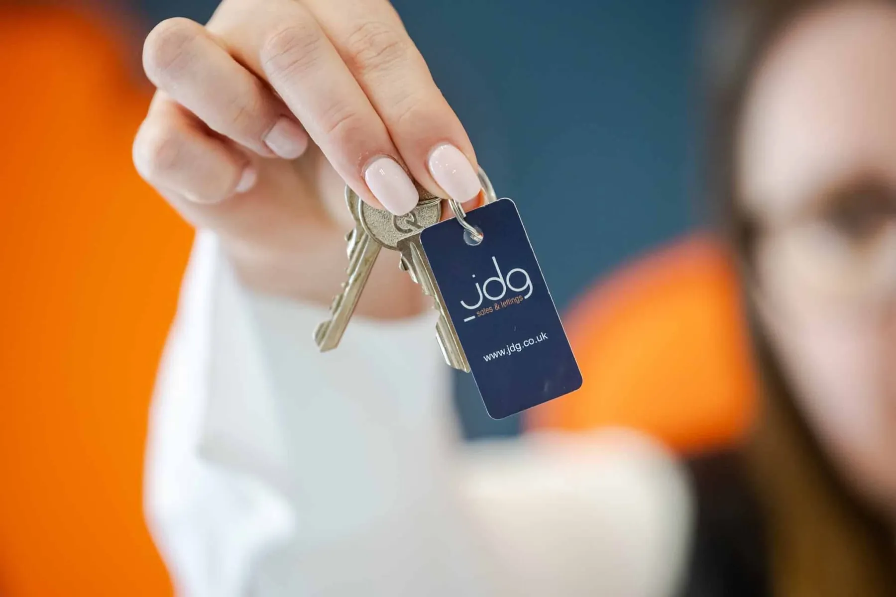 A member agent holding out a set of house keys on the agency's own keyring