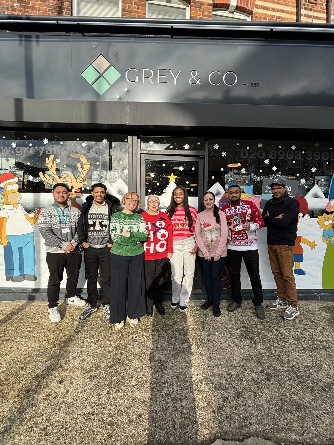 A member agency team in Christmas jumpers outside their office