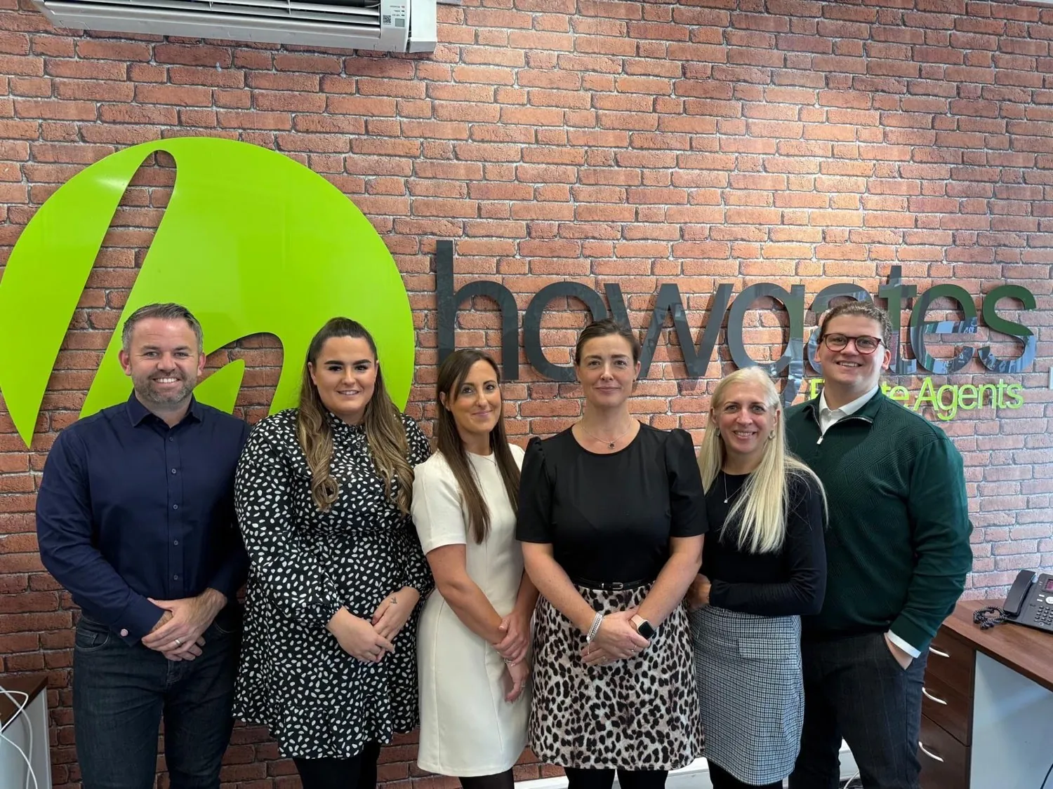 The Howgates team together in front of their own brand wall