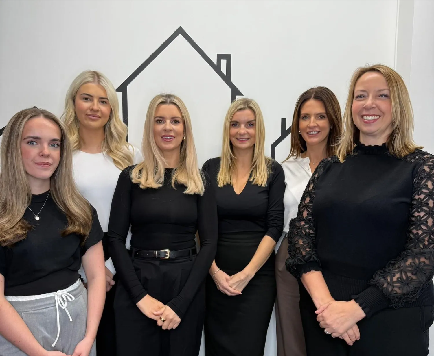The LL Estates team under a house outline painted on the wall