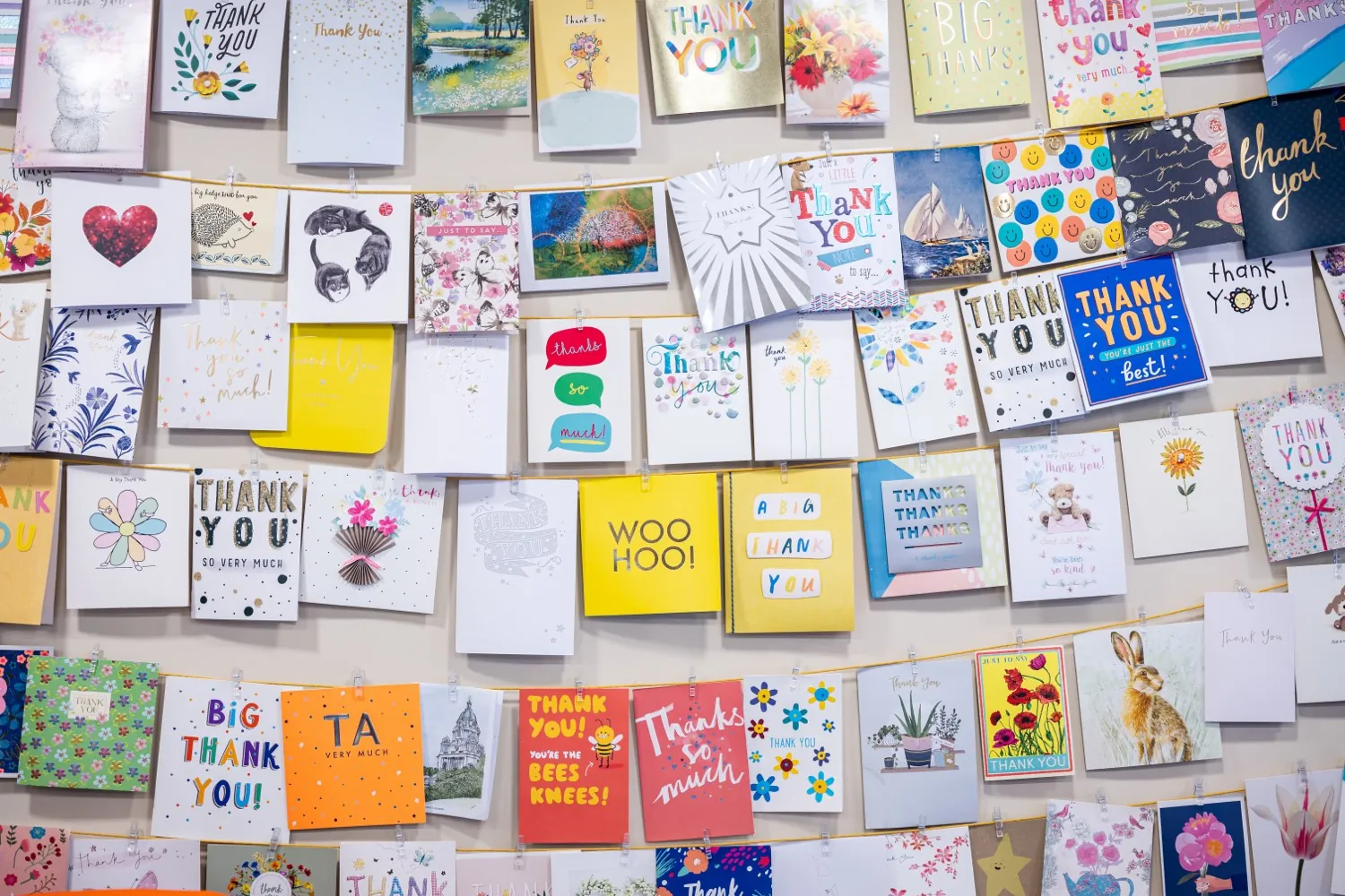 A wall covered edge to edge with handwritten thank you cards from clients