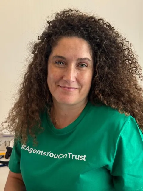 A member of Sacha Scott wearing the network's Agents You Can Trust shirt